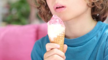 Tanınmayan kıvırcık çocuk dondurma yiyor. Dondurma yalayan çocuk