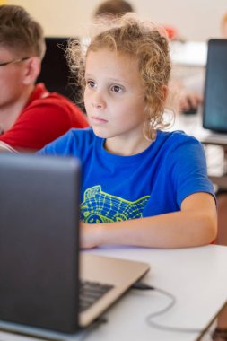 Okullu çocuk sınıfta kişisel bilgisayar kullanıyor. Çocuk bilgisayar bilimi dersi sırasında dijital kodlama programı öğreniyor.