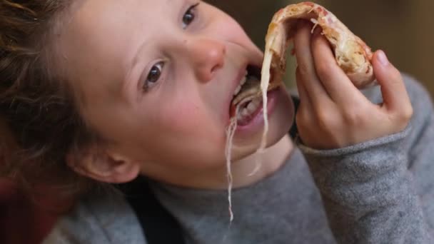スタイリッシュな子供の少年は喜んでチーズピザを食べています — ストック動画
