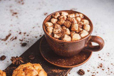 Bir fincanda krema ve beyaz masa üzerine kakao tozu serpilmiş tatlı ekmekleri olan sıcak çikolata içeceği..
