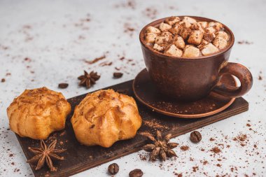 Bir fincanda krema ve beyaz masa üzerine kakao tozu serpilmiş tatlı ekmekleri olan sıcak çikolata içeceği..