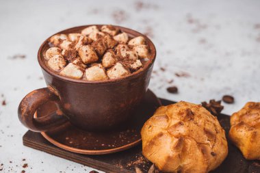 Bir fincanda krema ve beyaz masa üzerine kakao tozu serpilmiş tatlı ekmekleri olan sıcak çikolata içeceği..