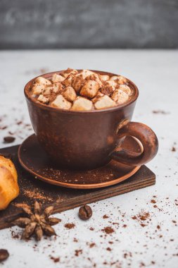Bir fincanda krema ve beyaz masa üzerine kakao tozu serpilmiş tatlı ekmekleri olan sıcak çikolata içeceği..
