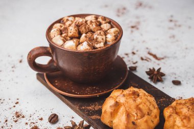 Bir fincanda krema ve beyaz masa üzerine kakao tozu serpilmiş tatlı ekmekleri olan sıcak çikolata içeceği..