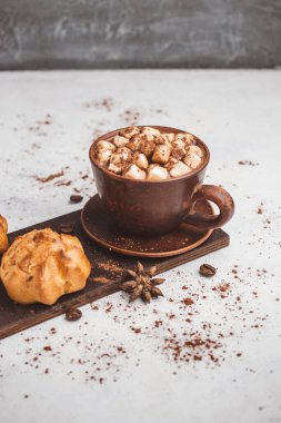 Bir fincanda krema ve beyaz masa üzerine kakao tozu serpilmiş tatlı ekmekleri olan sıcak çikolata içeceği..