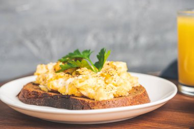 Beyaz tabakta maydanozlu yumurta, tahtadan yapılmış ev yapımı sağlıklı kahvaltı..