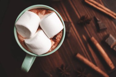 Sıcak çikolatalı içecek, marşmelovlu, ahşap tahtanın üstünde, üzerinde tarçın ve yıldız anason var..