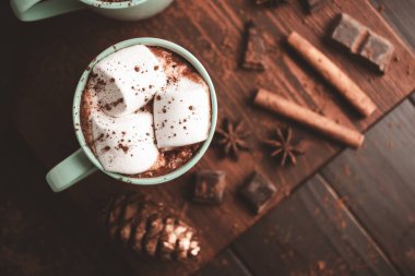 Sıcak çikolatalı içecek, marşmelovlu, ahşap tahtanın üstünde, üzerinde tarçın ve yıldız anason var..