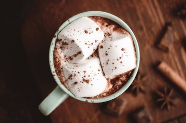 Sıcak çikolatalı içecek, marşmelovlu, ahşap tahtanın üstünde, üzerinde tarçın ve yıldız anason var..