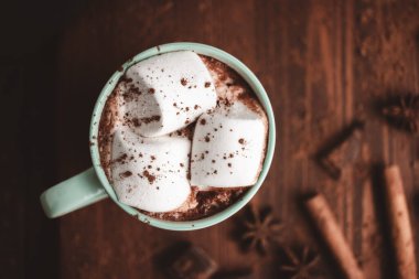 Sıcak çikolatalı içecek, marşmelovlu, ahşap tahtanın üstünde, üzerinde tarçın ve yıldız anason var..