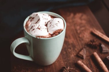 Sıcak çikolatalı içecek, içinde lokum olan tahta bir bardak, koyu arka plan..