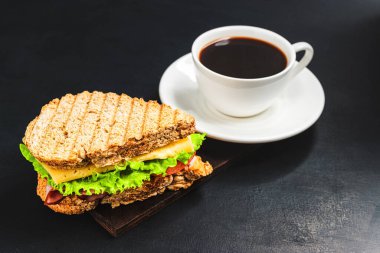 Peynirli ızgara sandviç, salata, salata, jambon ve koyu arkaplanda kahve fincanı. Kopyalama alanı ile öğle yemeği kavramı.