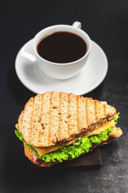 Peynirli ızgara sandviç, salata, salata, jambon ve koyu arkaplanda kahve fincanı. Kopyalama alanı ile öğle yemeği kavramı.