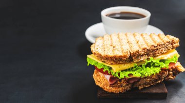 Peynirli ızgara sandviç, salata, salata, jambon ve koyu arkaplanda kahve fincanı. Kopyalama alanı ile öğle yemeği kavramı.