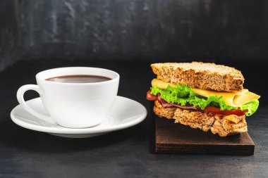 Peynirli ızgara sandviç, salata, salata, jambon ve koyu arkaplanda kahve fincanı. Kopyalama alanı ile öğle yemeği kavramı.