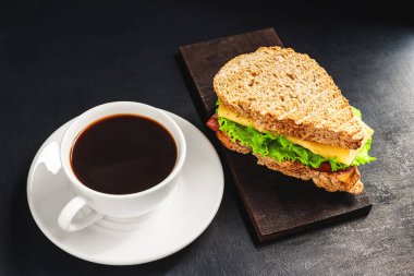 Peynirli ızgara sandviç, salata, salata, jambon ve koyu arkaplanda kahve fincanı. Kopyalama alanı ile öğle yemeği kavramı.