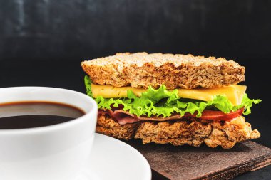 Peynirli ızgara sandviç, marul salatası, koyu arkaplanda jambon. Öğle yemeği konsepti.