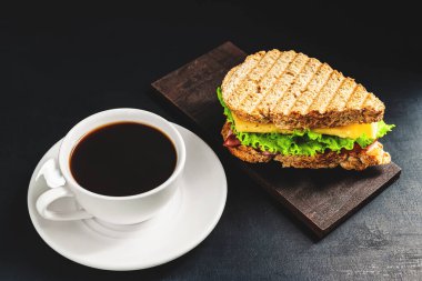 Peynirli ızgara sandviç, salata, salata, jambon ve koyu arkaplanda kahve fincanı. Kopyalama alanı ile öğle yemeği kavramı.