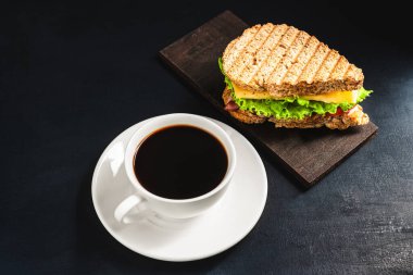 Peynirli ızgara sandviç, salata, salata, jambon ve koyu arkaplanda kahve fincanı. Kopyalama alanı ile öğle yemeği kavramı.