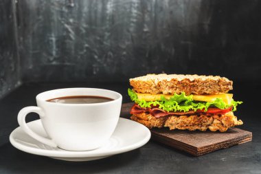 Peynirli ızgara sandviç, salata, salata, jambon ve koyu arkaplanda kahve fincanı. Kopyalama alanı ile öğle yemeği kavramı.