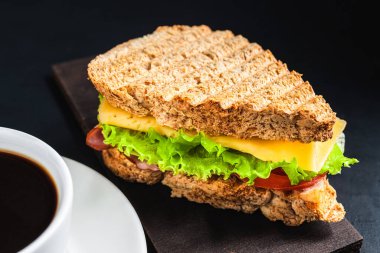 Peynirli ızgara sandviç, marul salatası, koyu arkaplanda jambon. Öğle yemeği konsepti.