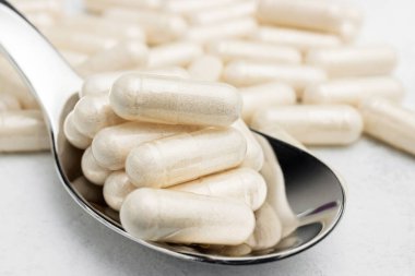 Beyaz ilaç kapsülleri, bir kaşıkta vitamin hapları veya ilaçlar, ilaç tedavisi, sağlık konsepti.