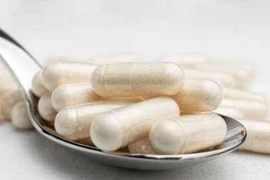 Beyaz ilaç kapsülleri, bir kaşıkta vitamin hapları veya ilaçlar, ilaç tedavisi, sağlık konsepti.