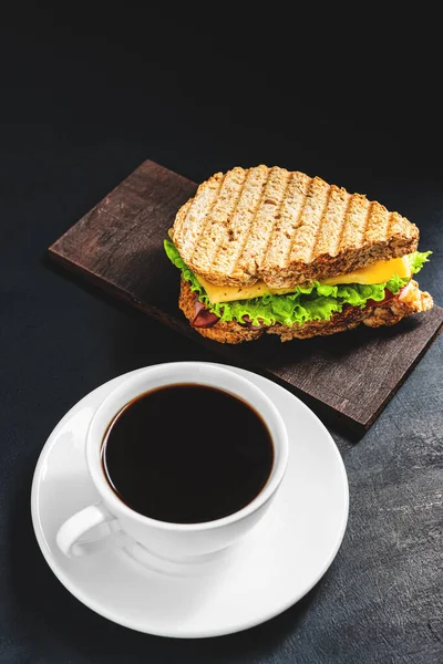 Peynirli ızgara sandviç, salata, salata, jambon ve koyu arkaplanda kahve fincanı. Kopyalama alanı ile öğle yemeği kavramı.