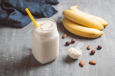 Banana smoothie with protein powder and nuts in a glass jar, healthy eating concept.