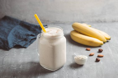 Banana smoothie with protein powder and nuts in a glass jar, healthy eating concept.