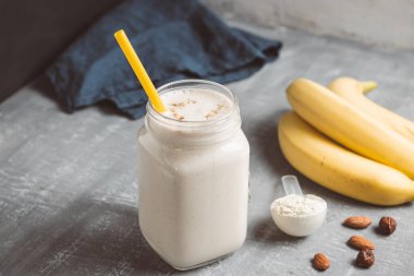 Banana smoothie with protein powder and nuts in a glass jar, healthy eating concept.