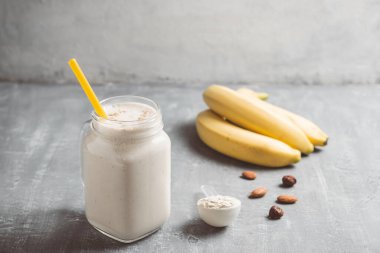Banana smoothie with protein powder and nuts in a glass jar, healthy eating concept.