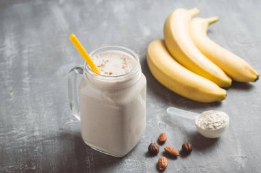 Banana smoothie with protein powder and nuts in a glass jar, healthy eating concept.