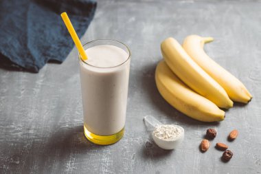 Banana smoothie with protein powder and nuts in a glass, healthy eating concept.