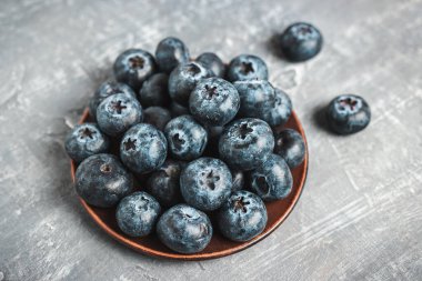 Fresh blueberries in a plate on a table, close up view.