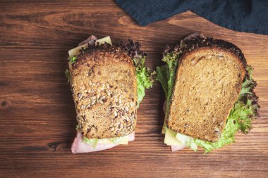 Sandwiches with a ham, cheese, tomato, salad lettuce on a wooden board , top view.