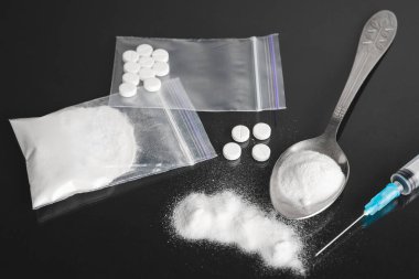 Karanlık arka planda ağır yasadışı uyuşturucular, kokain veya eroin beyaz toz, beyaz haplar, şırınga ve kaşık. Uyuşturucu bağımlılığı ve bağımlılık kavramı.