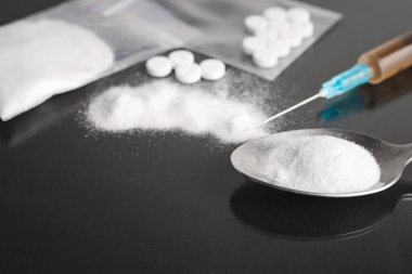 Karanlık arka planda ağır yasadışı uyuşturucular, kokain veya eroin beyaz toz, beyaz haplar, şırınga ve kaşık. Uyuşturucu bağımlılığı ve bağımlılık kavramı.