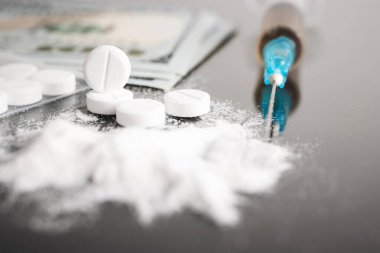Beyaz hap, ilaç ya da tıbbi tedavi, kokain ya da eroin beyaz toz, şırınga ve nakit para. Uyuşturucu bağımlılığı ve bağımlılık kavramı.