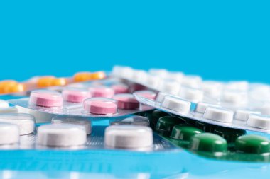 Mavi arka plan, sağlık ve tıp konseptine bağlı su toplayan ilaç ve tabletlerin yığını.