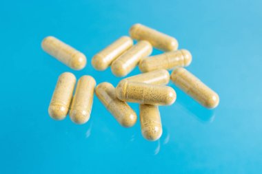 Sarı zerdeçal tedavi kapsülleri, mavi arka plan, ilaç ve sağlık hizmetleri kavramında tedavi için bitkisel vitamin hapları veya ilaçlar, yakın görüş.