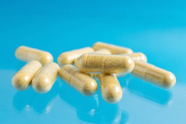 Sarı zerdeçal tedavi kapsülleri, mavi arka plan, ilaç ve sağlık hizmetleri kavramında tedavi için bitkisel vitamin hapları veya ilaçlar, yakın görüş.