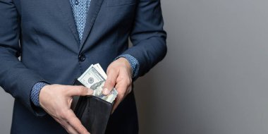 İyi giyimli bir adam deri cüzdanına, dolarlarına, Amerikan kağıt parasına bir sürü para koyar..