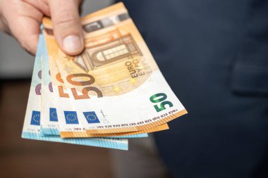 El ele tutuşan iyi giyimli bir adam ya da bir deste para veren, Euro banknotları, Avrupa Birliği kağıt para birimi.