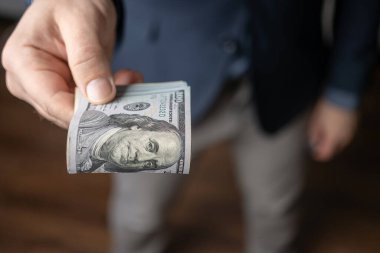 İyi giyimli bir adam elinde tutuyor ya da bir tomar para, dolar banknotları, Amerikan kağıt paraları veriyor..