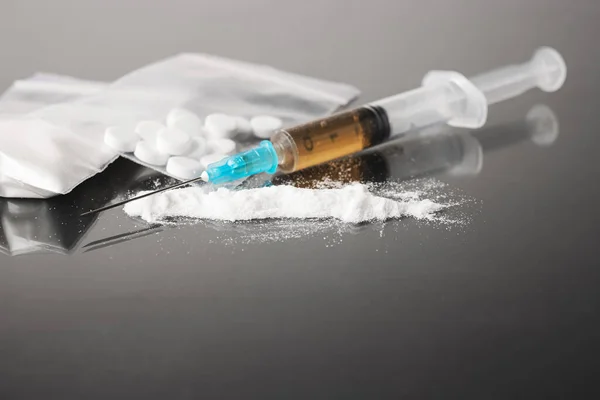 Stock image Drugs on dark background, cocaine or heroin white powder, white pills, syringe with a dose and us dollar cash. Drug abuse and addiction concept.