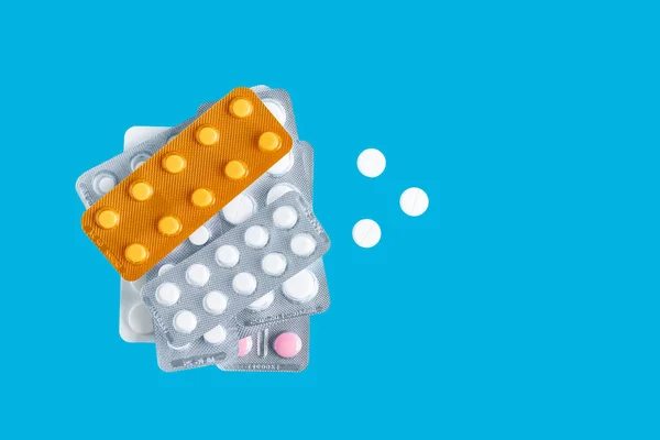 stock image Pile of various pills and tablets in a blister packs on blue background, top view, healthcare and medicine concept.