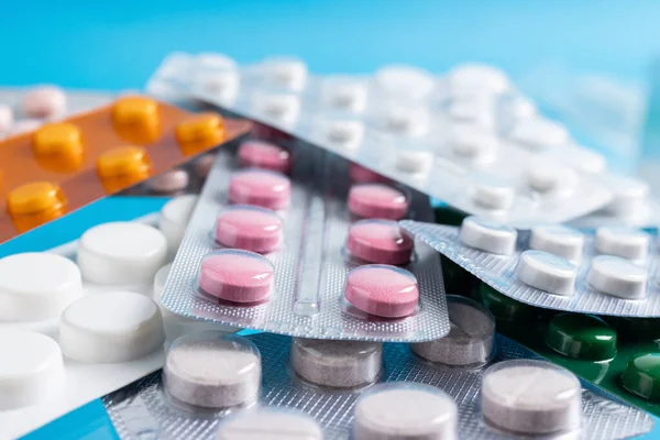 stock image Pile of various pills and tablets in a blister packs on blue background, healthcare and medicine concept.