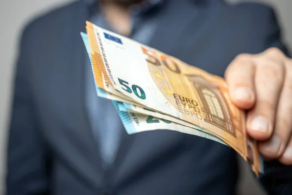 stock image Well dressed man holding in the hand or giving bunch of money, euro banknotes, European Union paper currency.