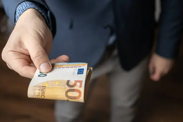 stock image Well dressed man holding in the hand or giving bunch of money, euro banknotes, European Union paper currency.